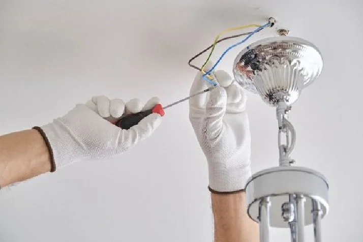 Person montiert Lampe an Decke